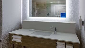 A modern bathroom with a large mirror, a white sink, and a towel rack.