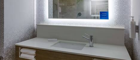 Un baño moderno con un espejo grande, un lavamanos blanco y un perchero para toallas.