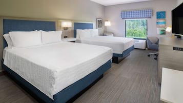 Ein Hotelzimmer mit zwei Betten, einem Schreibtisch, einem Stuhl und einem Fernseher.