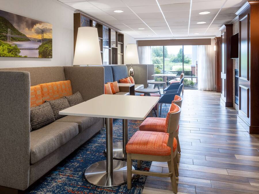 A hotel lobby with a sofa, table, chairs, and a large window offering a view of greenery.