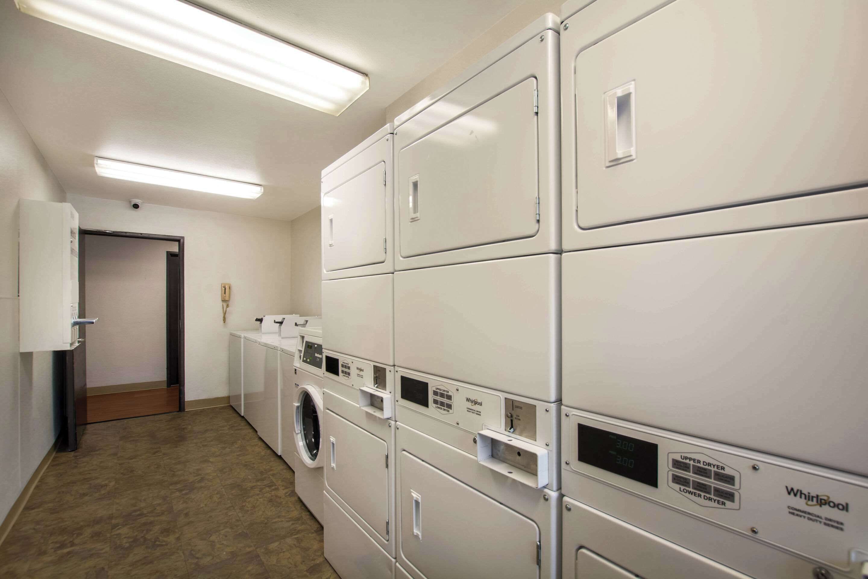 A laundry room with stacked washers and dryers, a door, and a wall-mounted light fixture.