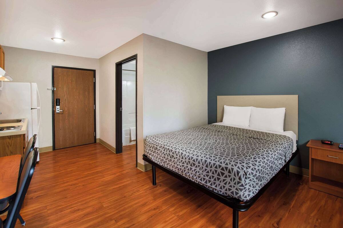 A bedroom with a bed, a desk, and a chair.