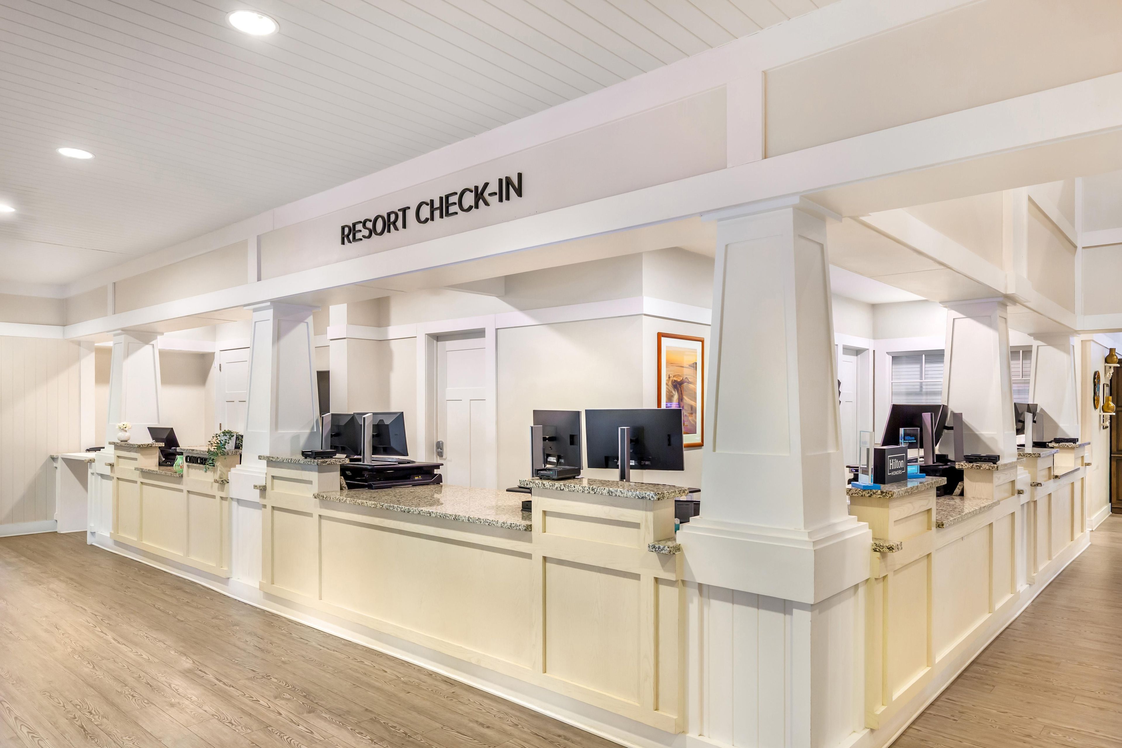 A resort check-in area with a reception desk, computers, and a framed picture on the wall.