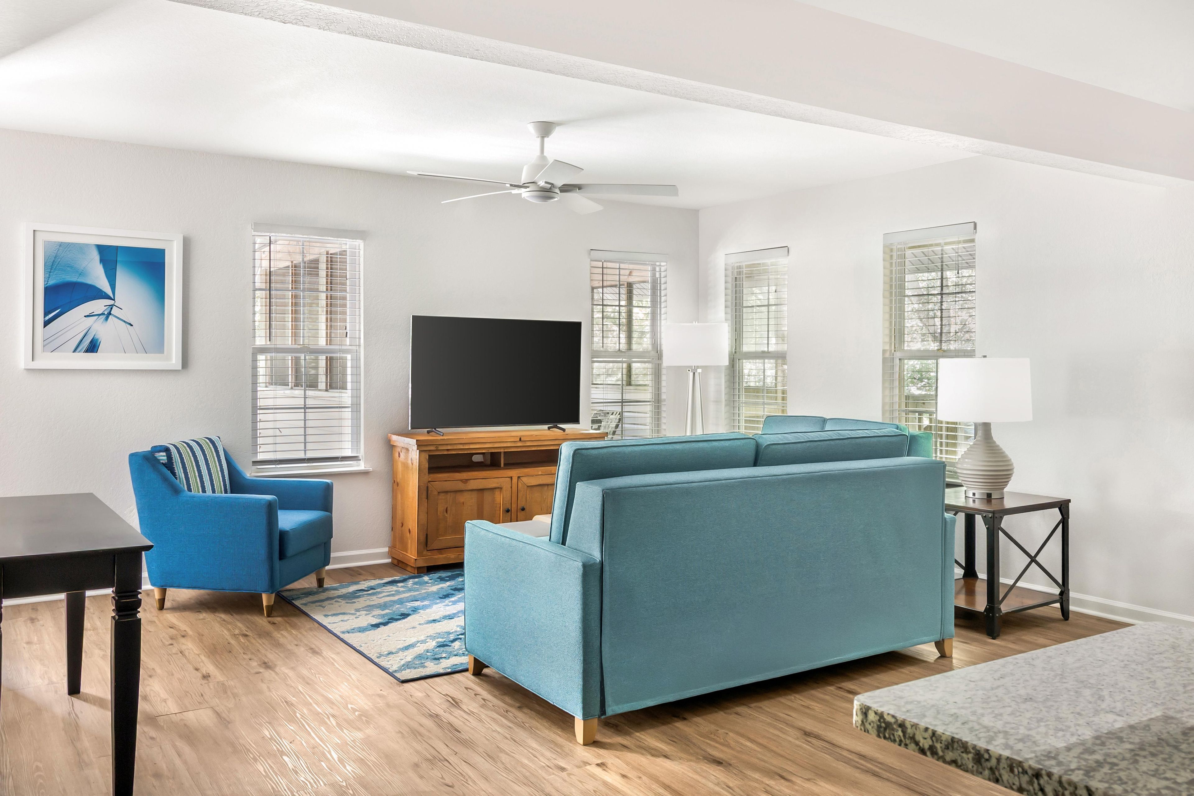 A modern living room with a sofa, a television, and a ceiling fan.
