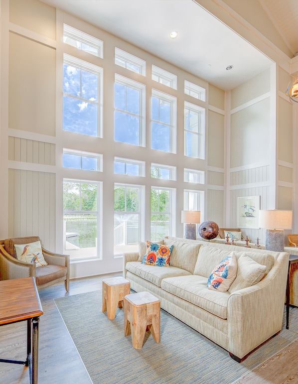 A spacious living room with a large window, a sofa, a wooden coffee table, and a chair.
