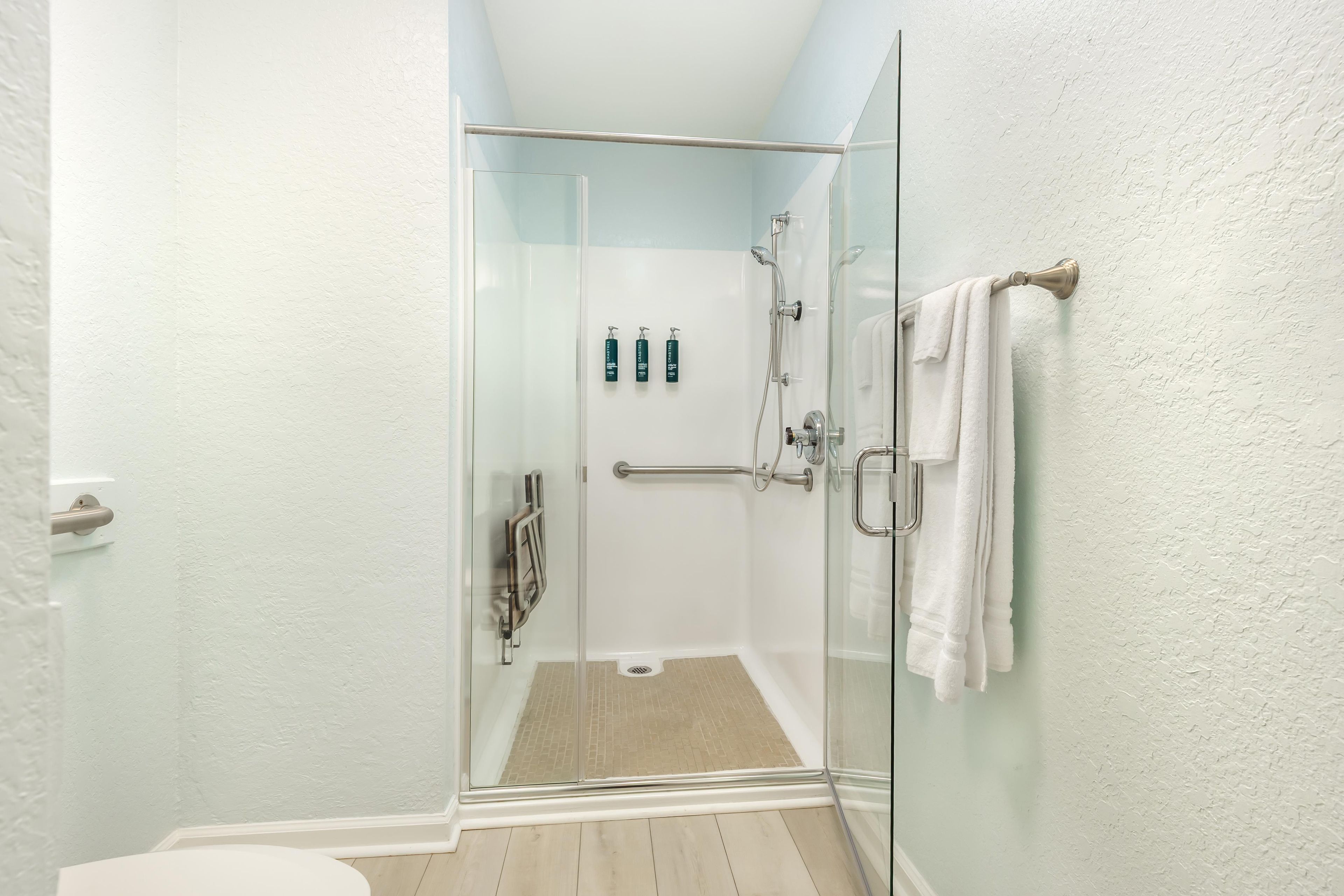 A glass-enclosed shower with a white towel rack, a glass door, and a visible shower control panel.