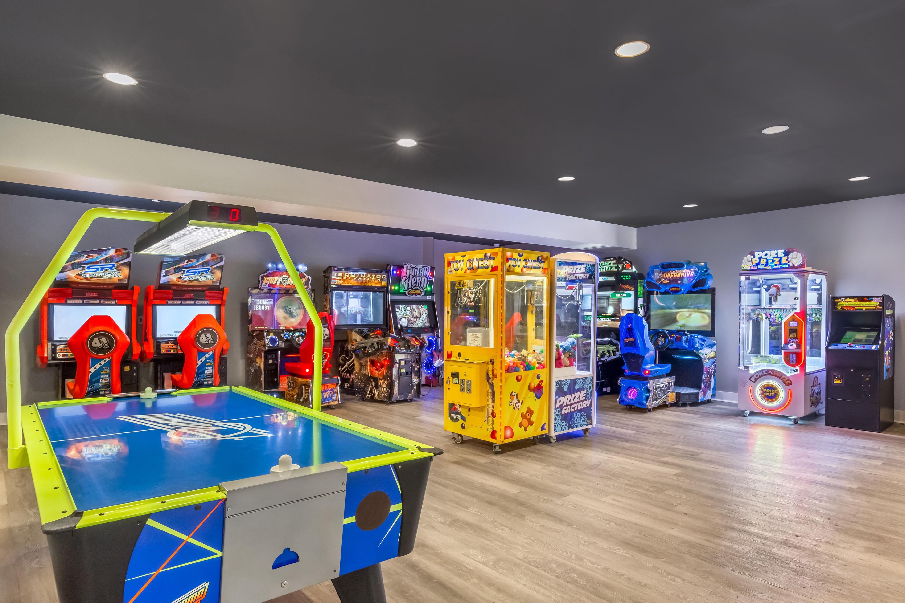 Une salle d’arcade intérieure proposant divers jeux, notamment un jeu de course, une machine à pinces et un jeu de boxe.