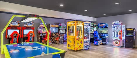 An indoor arcade with various gaming machines, including a racing game, a claw machine, and a boxing game.
