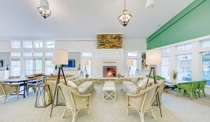 Un salón amplio con chimenea, mobiliario de mimbre y ventanas grandes.