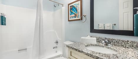 A bathroom with a bathtub, toilet, sink, and a large mirror.