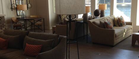 A spacious living room with large windows, a standing lamp, and a fireplace.