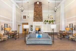 A spacious lobby with a high ceiling, stone accent wall, and multiple seating areas.