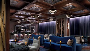 A modern lounge area with sofas, armchairs, and a bar.