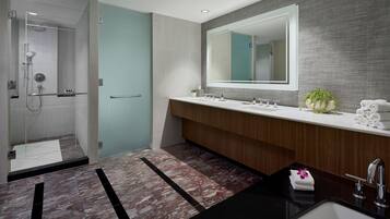 A modern bathroom with a glass-enclosed shower, a wooden vanity with a large mirror, and a black sink.