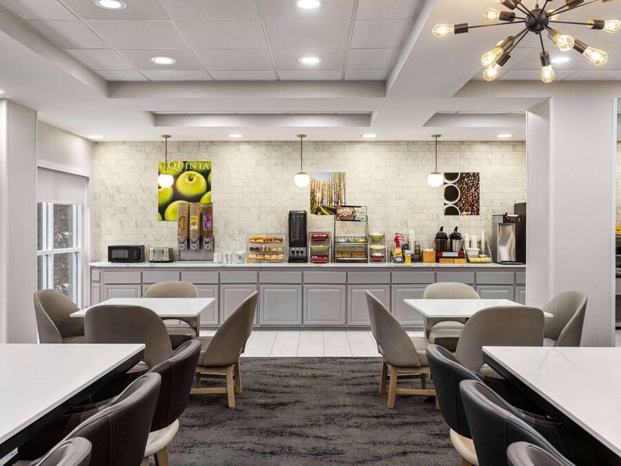 Un restaurante moderno con mostrador central, zona de estar y cocina al fondo.
