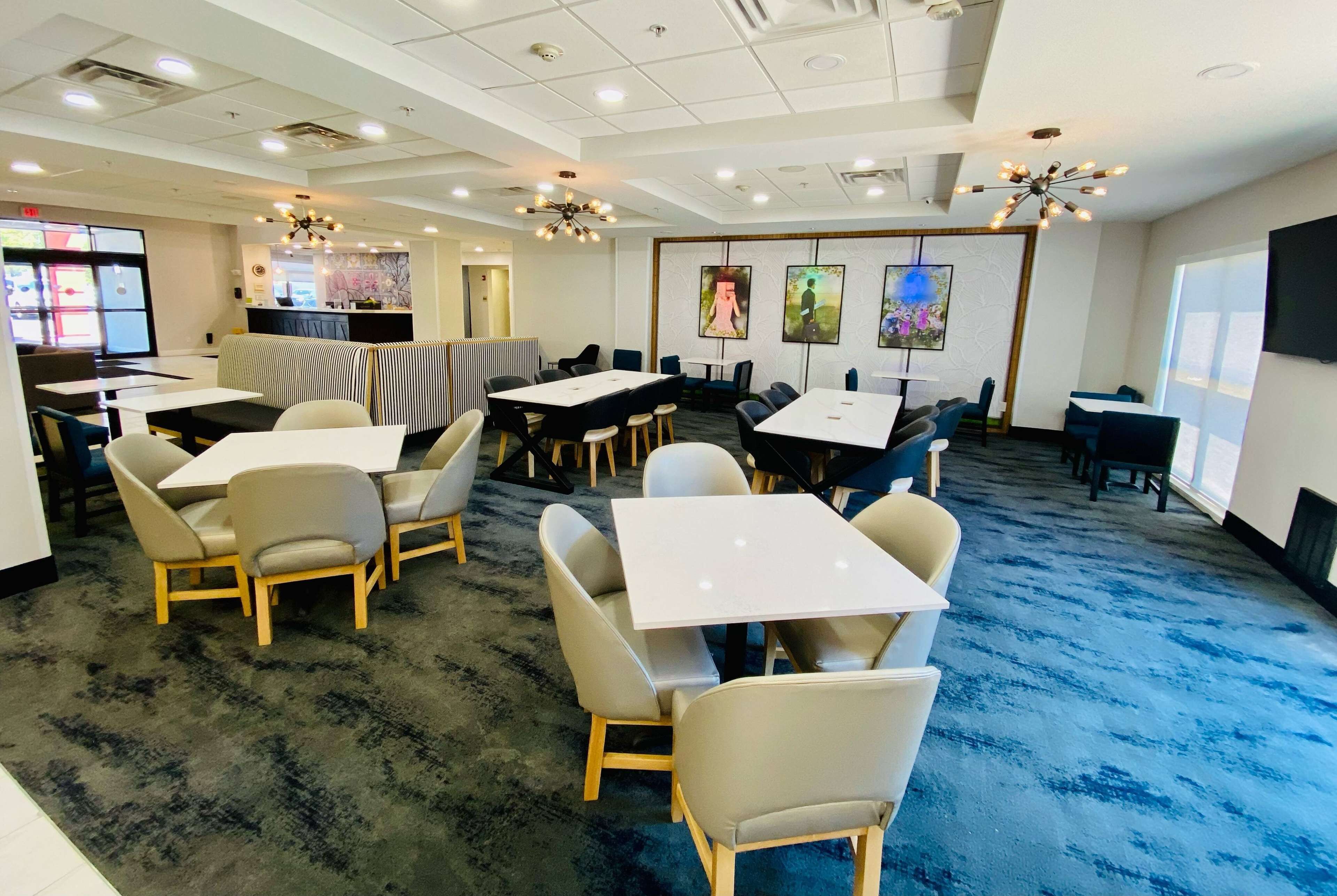 A conference room with tables and chairs, a carpeted floor, and artwork on the walls.