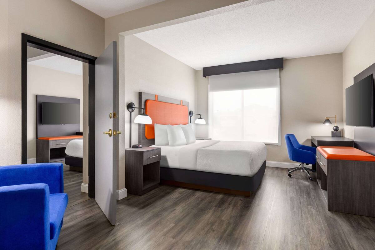 Une chambre d’hôtel avec un lit, un bureau, une chaise, une télévision et une fenêtre.