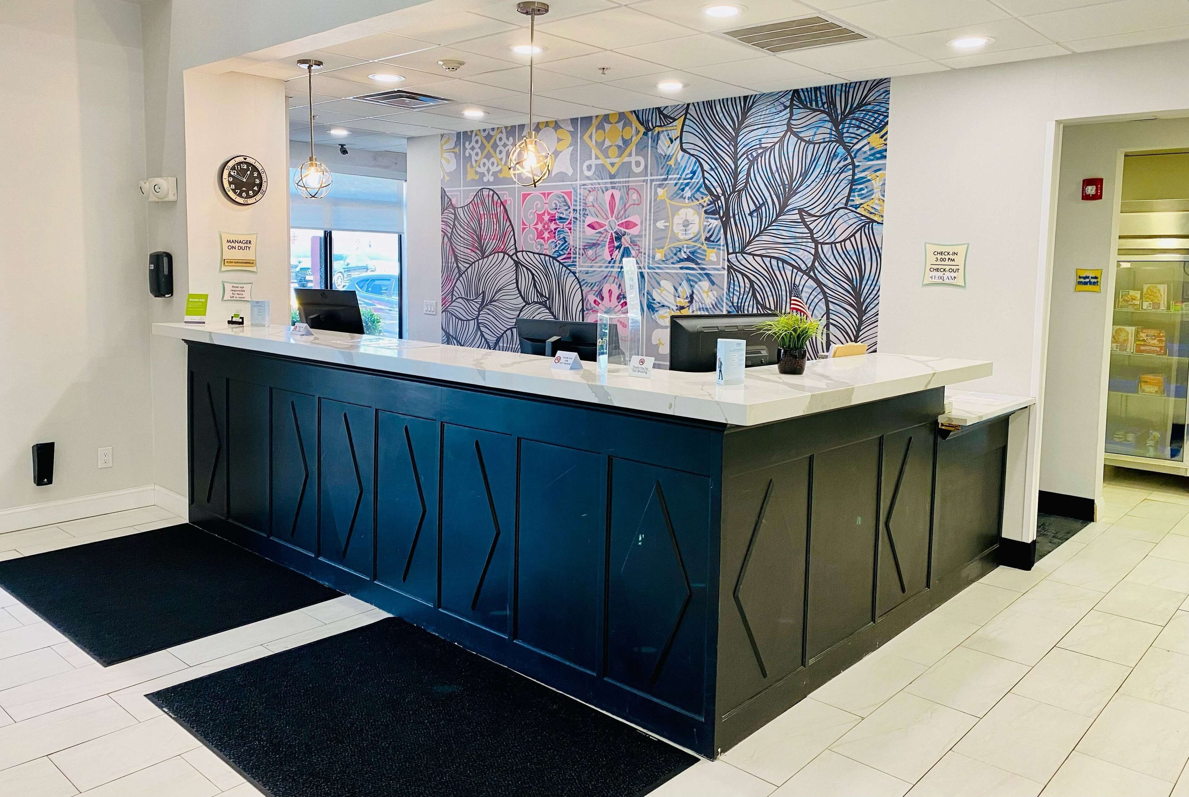 A reception desk with a modern design, a clock, and a sign indicating a manager on duty.