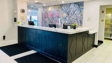 A reception desk with a modern design, a clock, and a sign indicating a manager on duty.