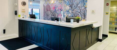 A reception desk with a modern design, a clock, and a sign indicating a manager on duty.