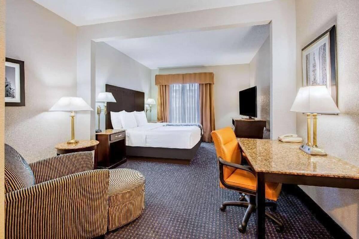 Une chambre d’hôtel comprenant un lit, un bureau, une chaise, un canapé et un téléviseur.