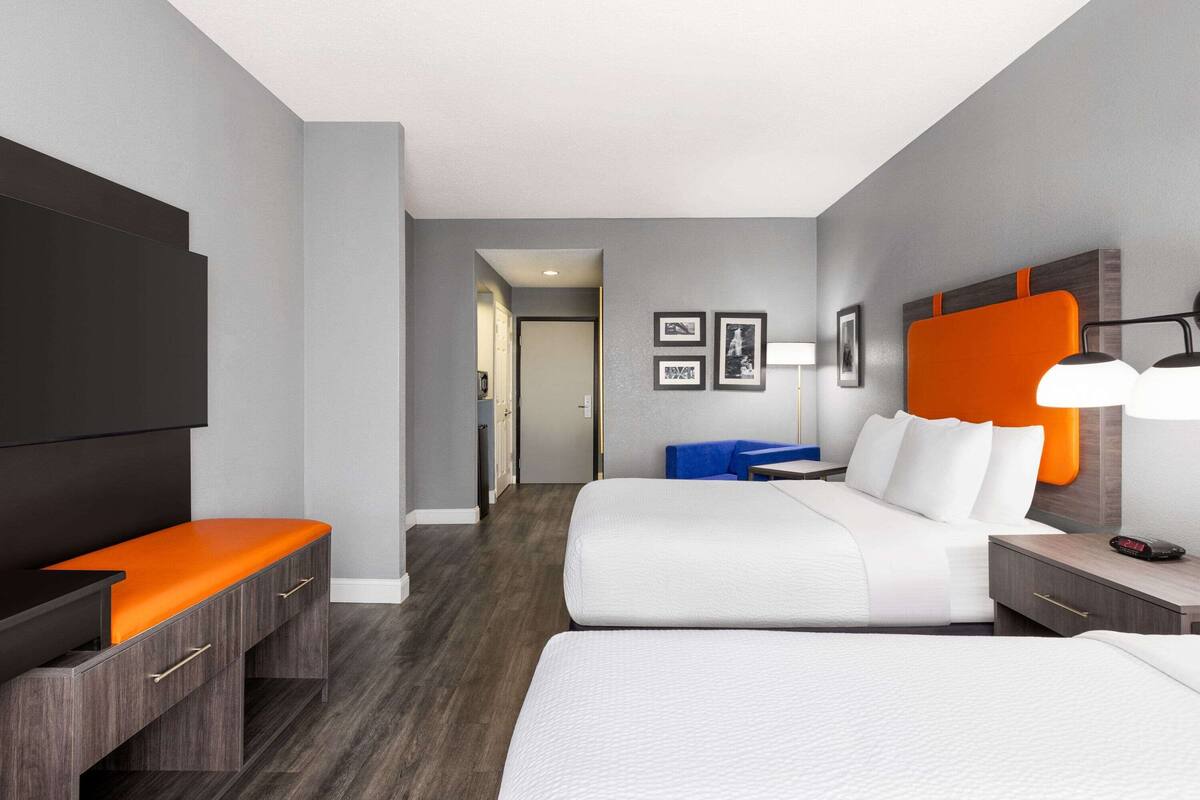 Une chambre d’hôtel moderne avec un grand lit, un bureau avec une chaise, une télévision et une petite table avec une lampe.