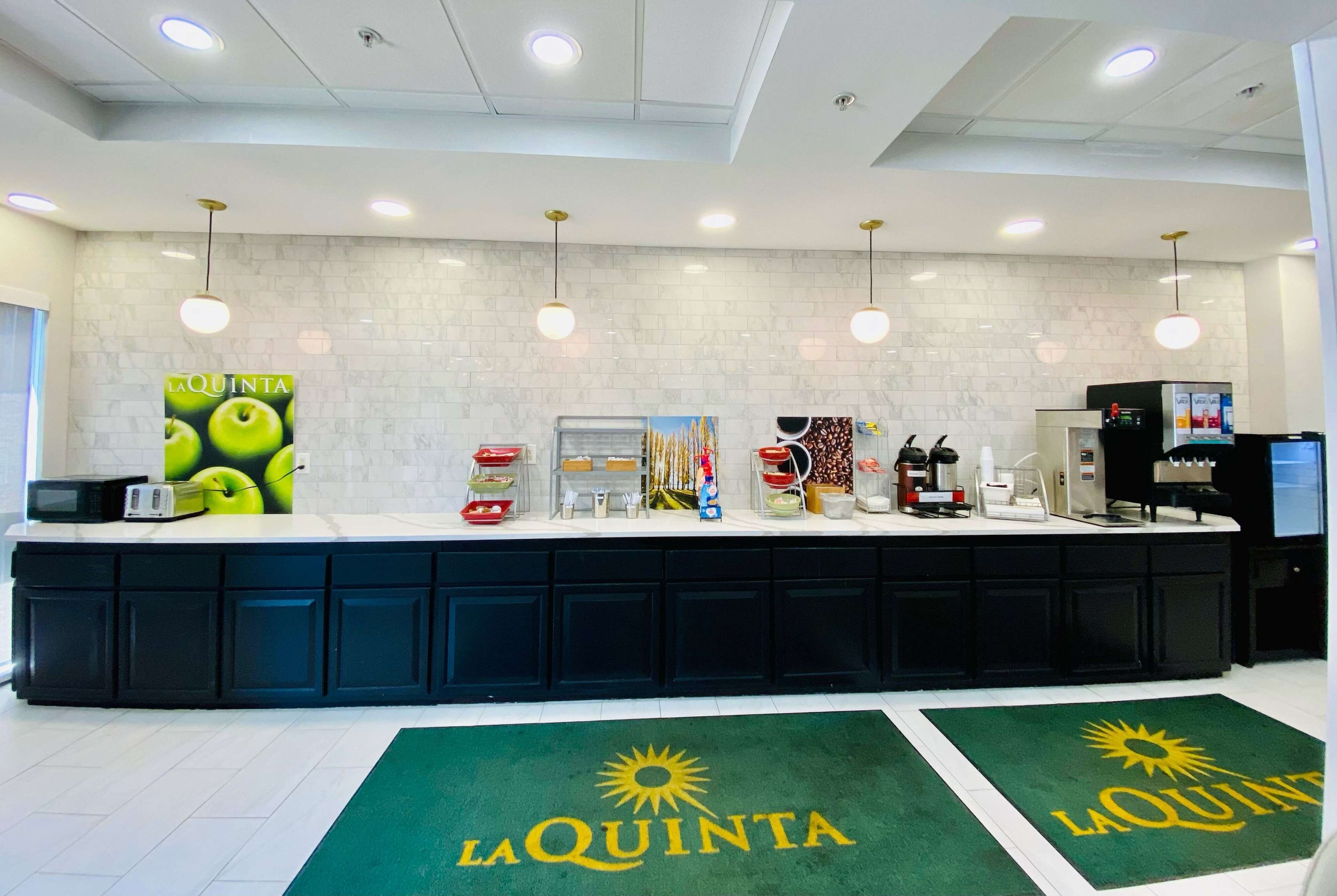 Un área de cocina moderna con mostrador, electrodomésticos y un tapete verde con el logotipo de 'La Quinta'.