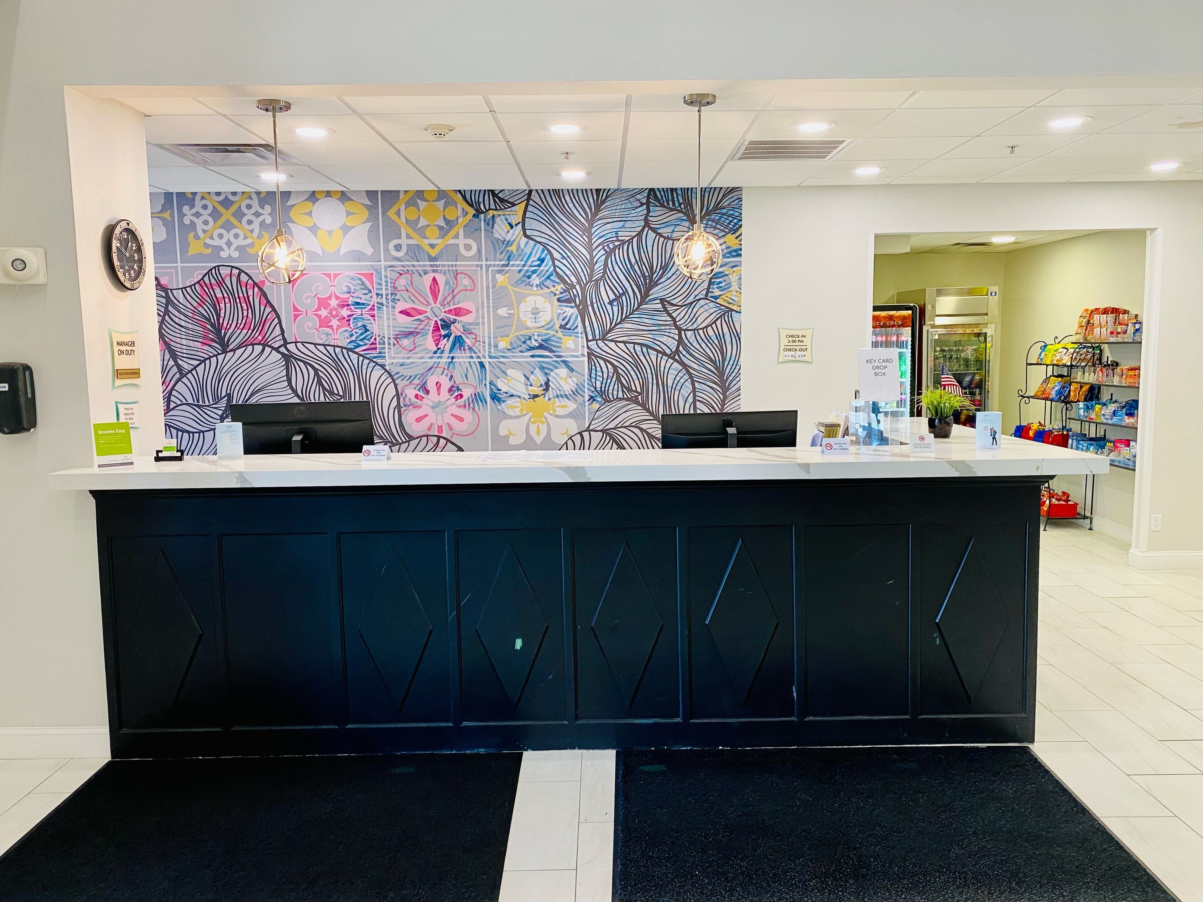 A reception area with a modern design, featuring a patterned wall, a black reception desk, and a check-in counter.