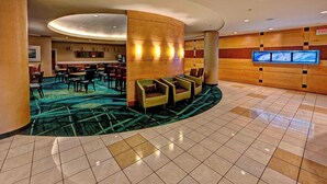 A lobby with a curved reception desk, multiple seating areas, a large flat-screen TV, and a patterned carpet. - SpringHill Suites Marriott Norfolk Old Dominion University (Norfolk)