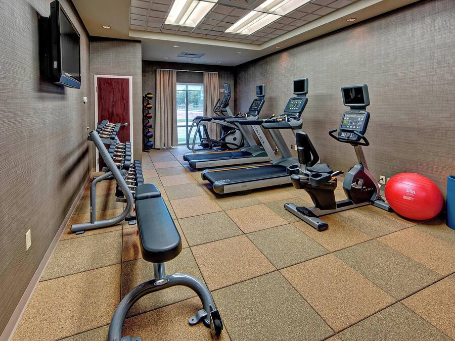 A gym with treadmills, elliptical machines, a bench, and exercise balls.