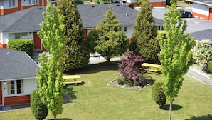 A residential area with multiple two-story houses, a central grassy area with a bench, and a small garden with various plants. - 2400 Motel (Vancouver)