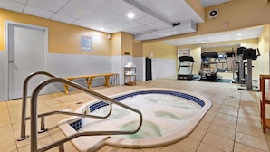A pool area with a hot tub, exercise equipment, and a bench. - Coast Fraser Inn (Williams Lake)