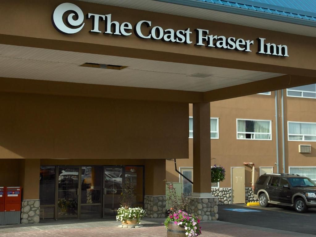 The Coast Fraser Inn with a clear entrance, a parking area, and a stone wall.