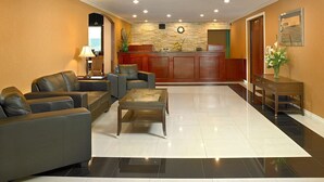 A hotel lobby with leather sofas, a coffee table, a reception desk, and a stone wall. - Coast Fraser Inn (Williams Lake)