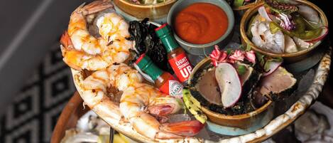 Una bandeja de mariscos con camarones, ostras, mejillones y diversas guarniciones.
