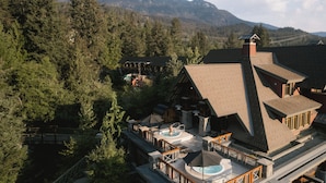 A lodge with a pool, outdoor seating, and a mountain backdrop.