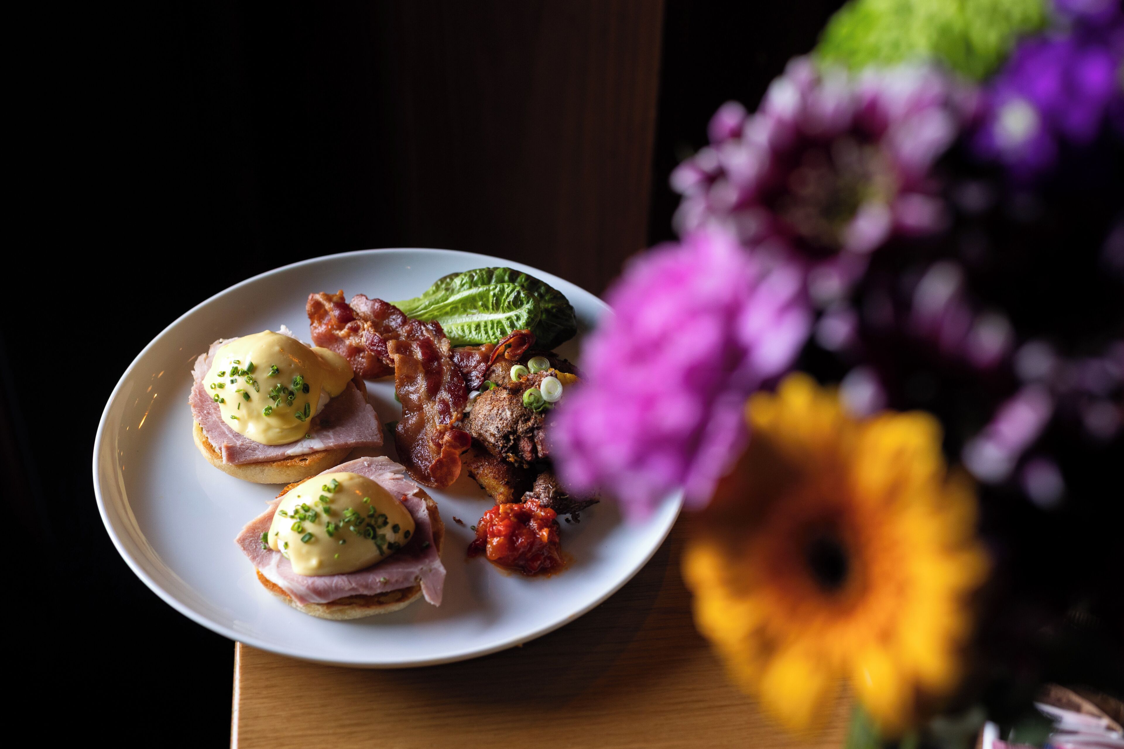 A plate with food items, a flower, and a wooden surface.