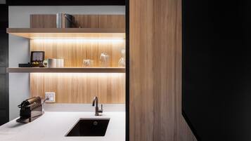 A modern kitchen with a stainless steel sink, wooden shelves, and a coffee machine.