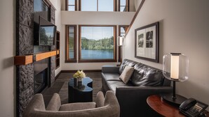 A modern living room with a fireplace, a sofa, a coffee table, and a desk with a phone.