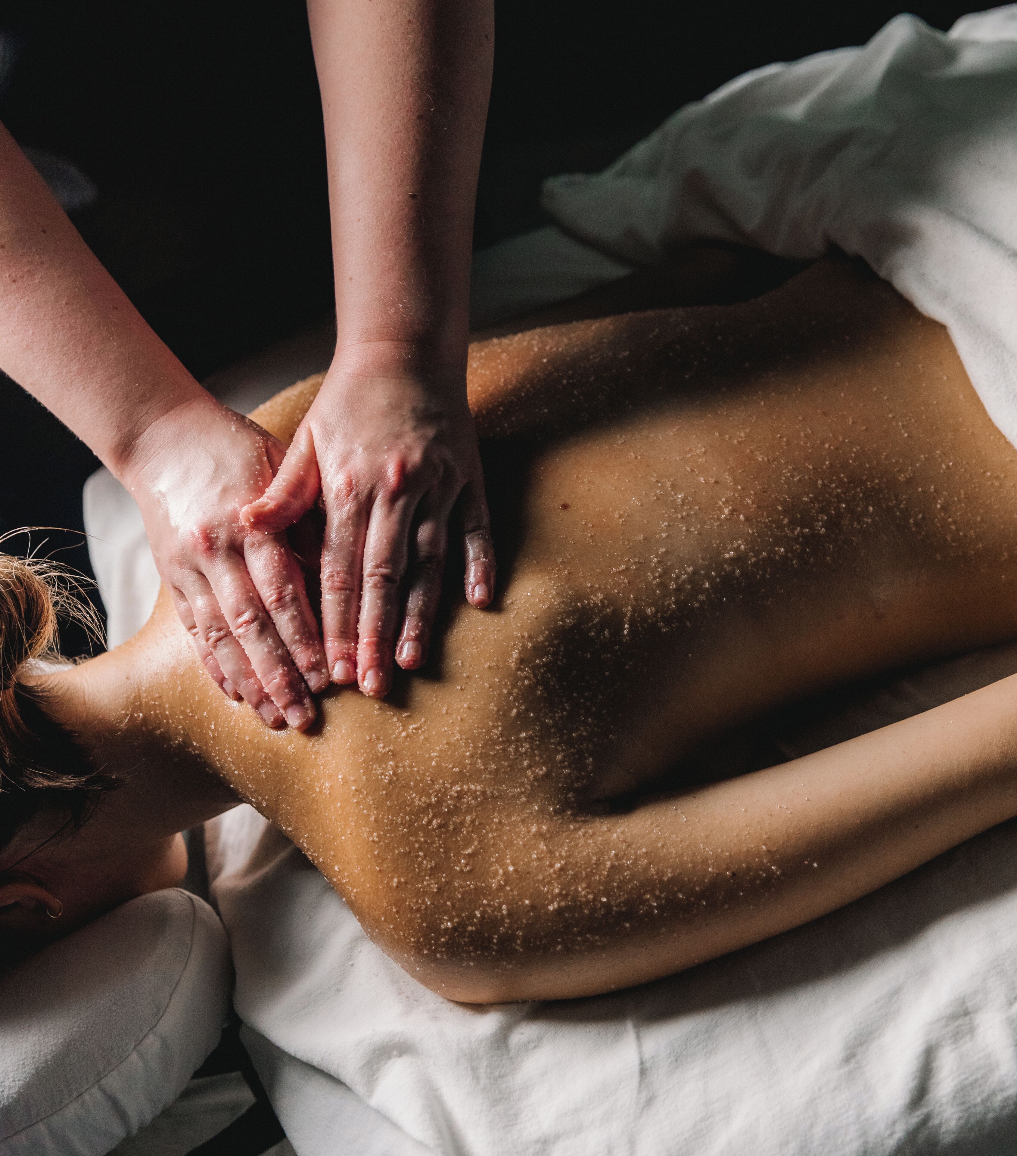Iemand ontvangt een rugmassage op een bed.