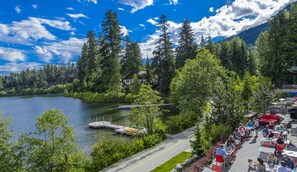 A lakeside view with a dock, outdoor seating, and a mountain backdrop. - Nita Lake Lodge (Whistler)