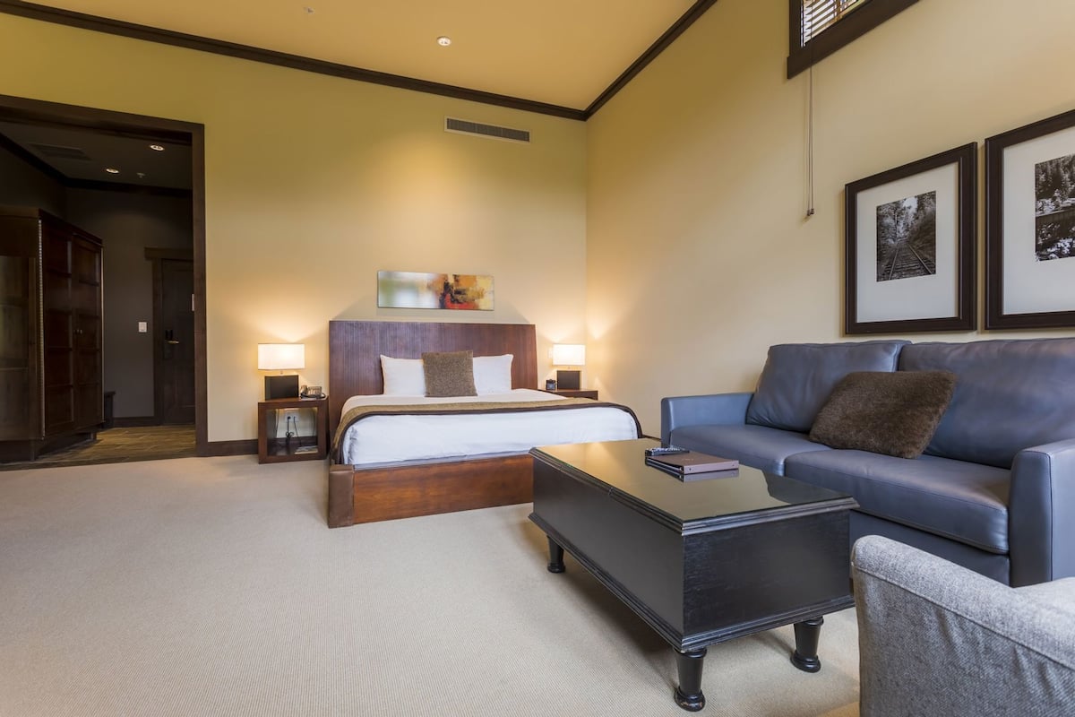 Een hotelkamer met een bed, een slaapbank, een salontafel en twee bedlampjes.