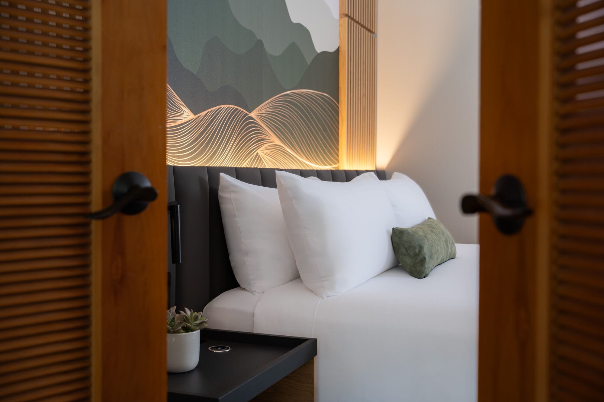 Een moderne slaapkamer met een witte bank, een groen kussen, en een wandlamp.
