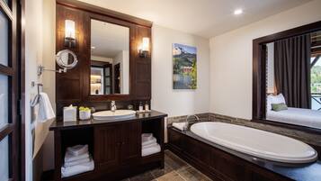 A modern bathroom with a large mirror, two sinks, a bathtub, and a window with curtains.