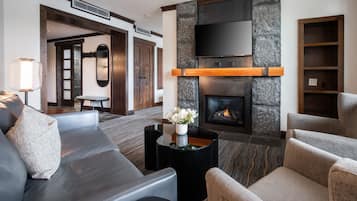A modern living room with a stone fireplace, leather sofas, and a small table with a vase of flowers.