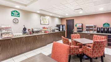 A breakfast area with a counter, seating, and coffee machines.