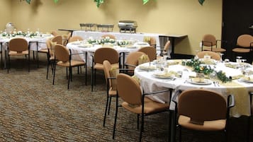 A banquet hall with round tables set for dining, arranged in rows.