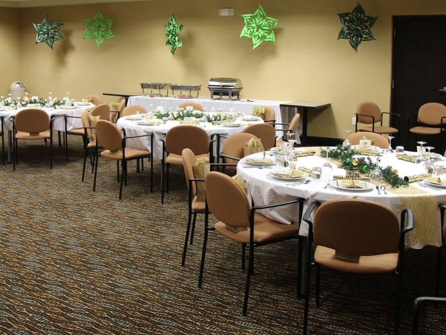 A banquet hall with round tables set for dining, arranged in rows.
