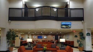Un hall d’entrée spacieux avec un plafond haut, un balcon et un téléviseur fixé au mur.