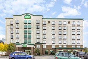 Un hotel de varios pisos con fachada verde y beige, múltiples ventanas y un letrero que dice 'Wingate by Wyndham'.